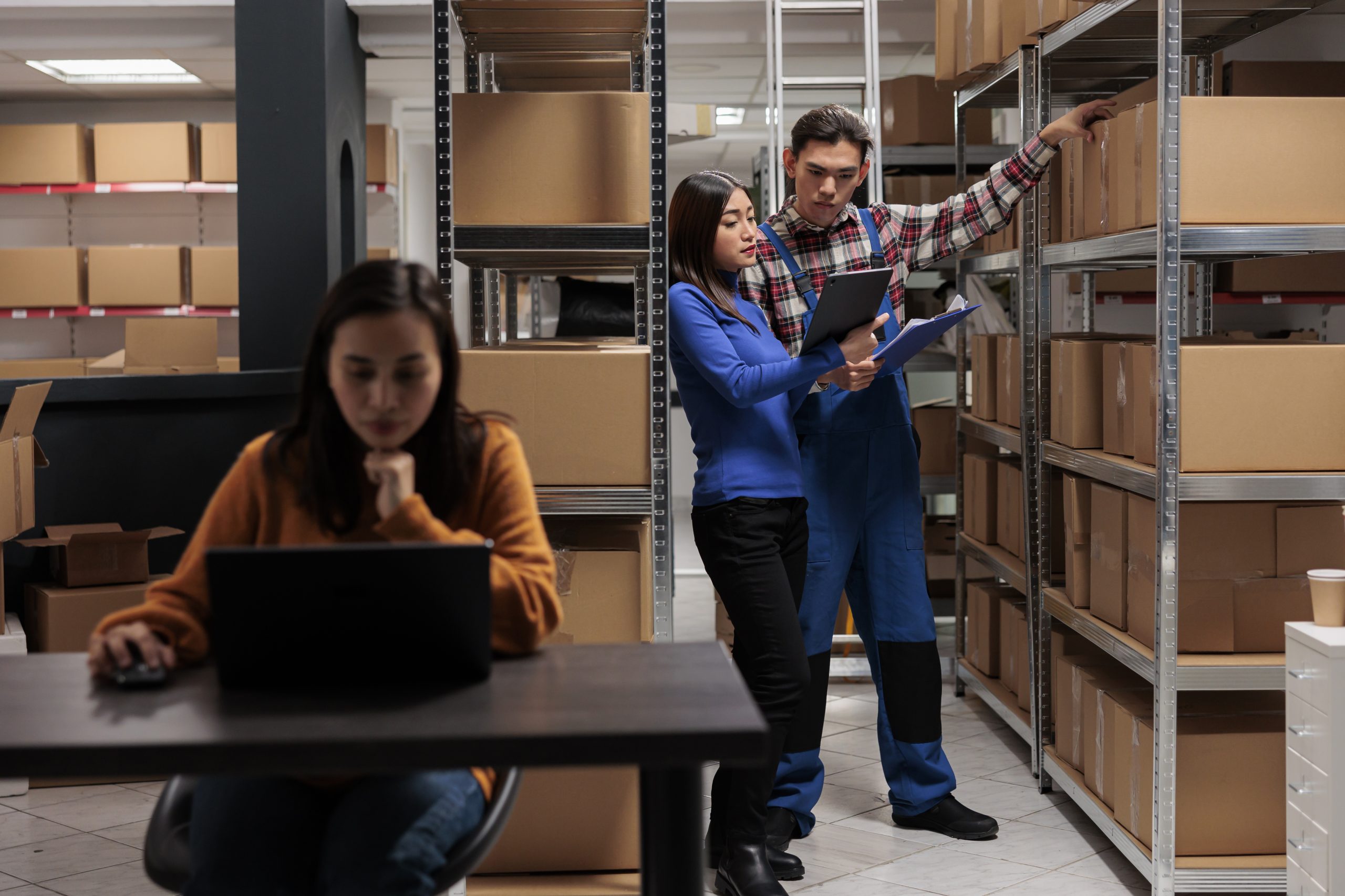 Warehouse worker and logistics manager doing products audit in storage room. Storehouse employees managing goods parcels quality control while analyzing data in clipboard and digital tablet